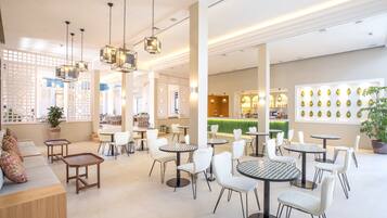 A spacious indoor area with multiple seating arrangements, including round tables and chairs, and a central area with a counter and chairs.