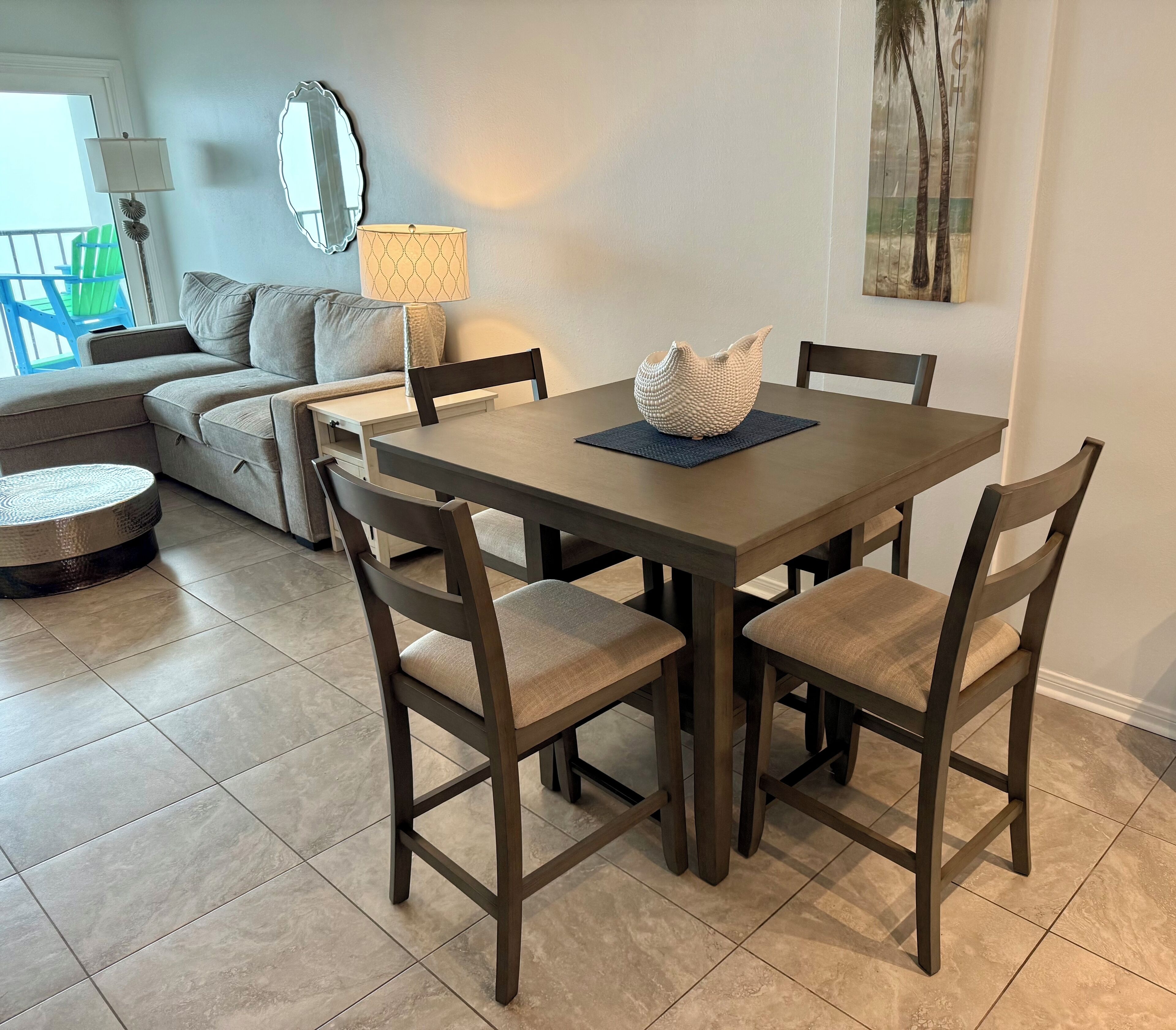 A dining area with a square table, four chairs, and a decorative vase.