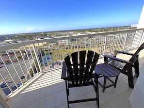 Enjoy the serene view of the neighborhood from this balcony, featuring two Adirondack chairs and a small table.