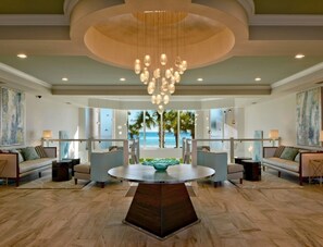 Experience the elegant lobby with a central table, comfortable seating, and stunning views of palm trees and the sky.