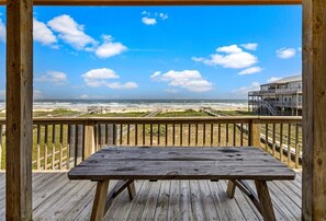 Eine Holzterrasse mit Picknicktisch mit Blick auf einen Strand und den Ozean.