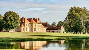 A large, historic building with multiple wings and a pond in front. - Château des Louteaux (Chézy)