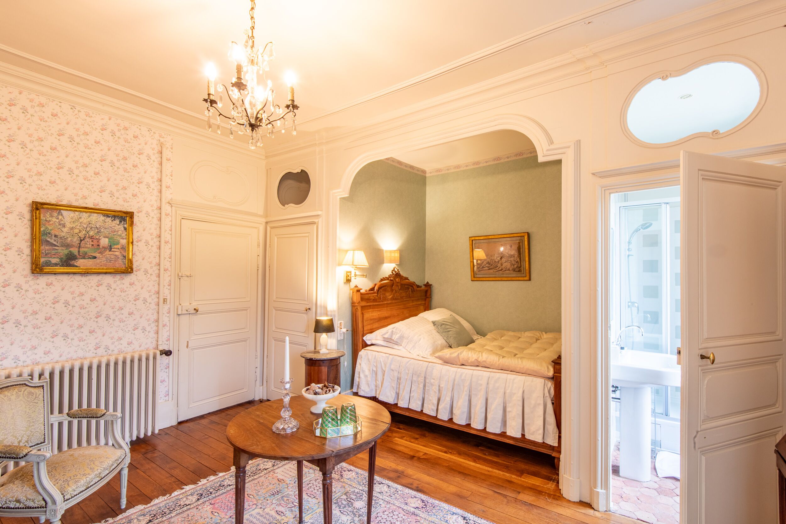 Quarto com cama de madeira, um candelabro, radiador e uma cadeira.