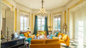 A spacious room with a grand chandelier, a piano, and a checkered floor. - Château des Louteaux (Chézy)