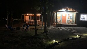 Pieni, valaistu ulkotila, jossa on puinen terassi ja muutama tuoli.