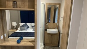 A bedroom with a bed, bedside table, lamp, and decorative pillows. - Clouded Yellow - Beautiful Modern Lodge, Kippford (Dalbeattie)