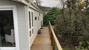 A wooden deck with a railing, a white exterior wall, and a window. - Clouded Yellow - Beautiful Modern Lodge, Kippford (Dalbeattie)