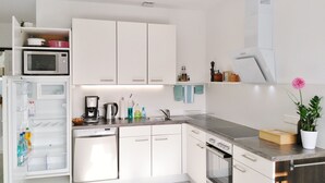 A modern kitchen with white cabinets, a microwave, a coffee maker, a sink, and an oven.