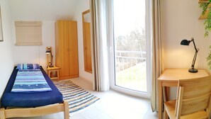 A room with a bed, a desk, a chair, a lamp, a window, and a door.