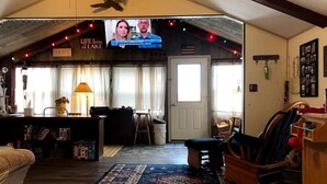 Ein gemütliches Wohnzimmer mit Fernseher, Kamin und rustikalen Einrichtungsgegenständen.