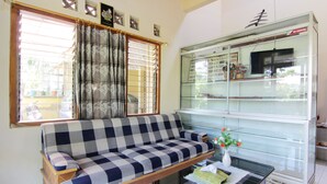 Una sala de estar con un sofá, un aparador de vidrio y una ventana con cortinas.