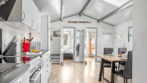 Ett modernt kök med vita köksskåp, en inbyggd ugn och en matplats med ett träbord och stolar.
