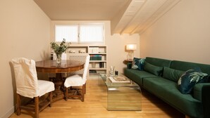 A cozy living room with a round wooden dining table, a green sofa, and a bookshelf. - San Jacopo Top by Mmega (Florence)