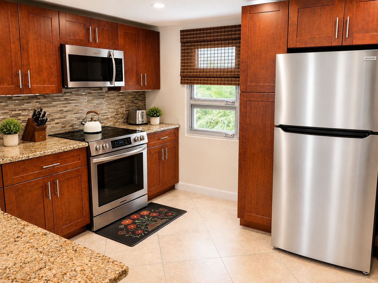 A kitchen with wooden cabinets, stainless steel appliances, a microwave, a toaster, and a refrigerator.