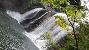 A waterfall cascading over rocks into a body of water, surrounded by lush greenery. - Riverston Lodge (Matale)