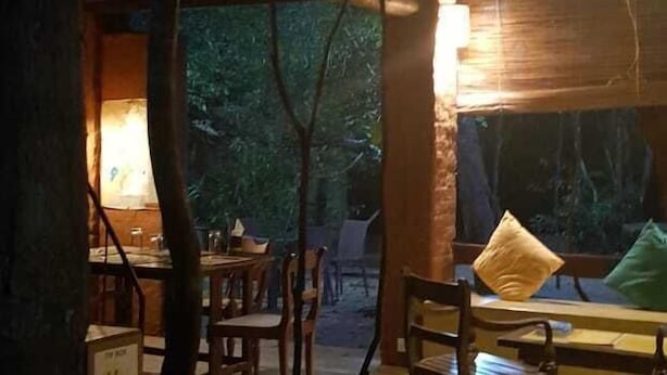 A rustic wooden interior with a dining area, wooden furniture, and hanging lights. - Riverston Lodge (Matale)