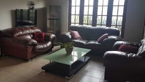 A living room with two leather sofas, a glass coffee table, and a TV. - Riverston Lodge (Matale)
