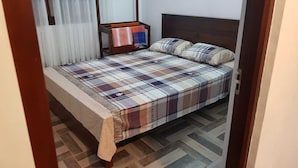 A bedroom with a bed, a nightstand, and a window with curtains. - Riverston Lodge (Matale)