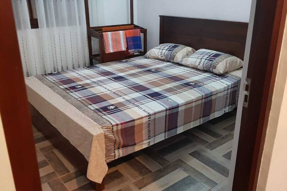 A bedroom with a bed, a nightstand, and a window with curtains.