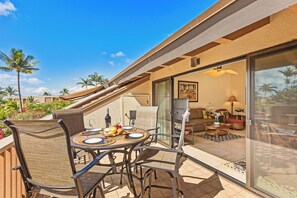 An outdoor patio with a dining table, chairs, and a grill area. - Fully Renovated Kihei 2BR Condo New AC Tropical Grounds Waterfall Pool (Kihei)