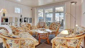 A cozy living room with wicker furniture, a glass coffee table, and a TV on the wall. - 3 bedroom gorgeous home in Vordingborg (Vordingborg)