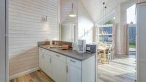 Une cuisine moderne avec des meubles blancs, un plan de travail en bois et un coin repas comprenant une table et des chaises.