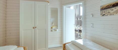 Ein Schlafzimmer mit zwei Holzbetten, einem weißen Kleiderschrank und einer Tür zu einem Badezimmer.