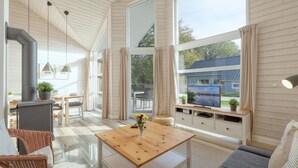 Un intérieur de chalet chaleureux avec un coin repas, un canapé et un téléviseur.