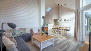 Un vaste espace de vie agrémenté d’une cheminée moderne, d’une table à manger et d’un coin salon confortable.