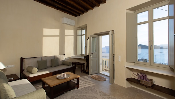 A living room with a sofa, coffee table, and a view of the sea through large windows.