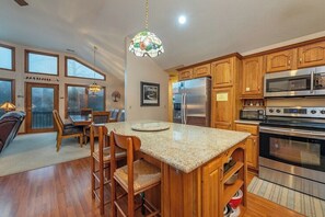 A kitchen with wooden cabinets, granite countertops, stainless steel appliances, and a dining area with a table and chairs.