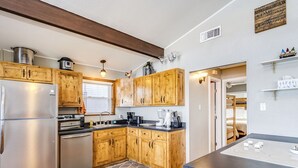Una cocina con gabinetes de madera, un refrigerador de acero inoxidable, una estufa y una cafetera.