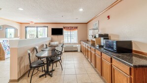 A kitchen with a dining table, chairs, a microwave, and a TV. - Fairway Inn (La Porte)