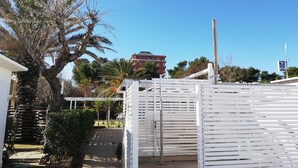 Una entrada tancada amb una valla blanca, una palmera i un edifici al fons.
