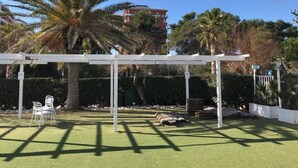 Zona exterior coberta amb gespa artificial, cadires blanques i una estructura de pergola.