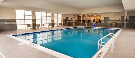Ein Hallenschwimmbad mit klarem Wasser, einer weißen Poolleiter und gefliestem Boden.