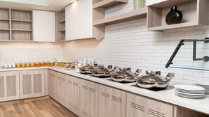 Una cocina moderna con armarios blancos, encimera de madera y electrodomésticos de acero inoxidable.