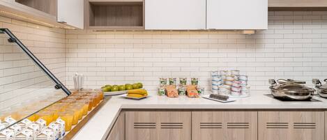 Een keuken met een ontbijtbalkje, voorzien van sappen, fruit en verpakte etenswaren.