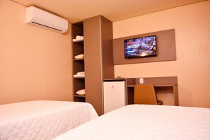 A hotel room with two beds, a TV mounted on the wall, a minibar, and a built-in air conditioner. - Forte Express (Macapa)