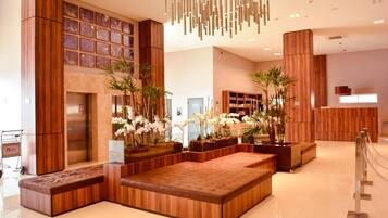 A modern lobby with wooden paneling, a seating area, and a reception desk.