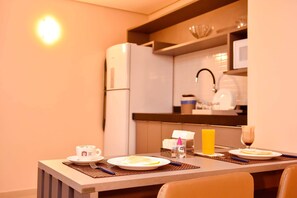 Quarto de hotel com uma mesa de jantar posta para o café da manhã, incluindo pratos, uma xícara e um copo de suco.