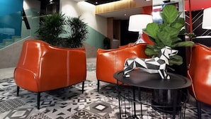 A modern lobby with leather seating, a patterned floor, and a geometric sculpture on a table. - Sovotel Conezion Putrajaya (Serdang)