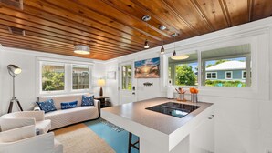 Una cocina moderna con una isla central, muebles blancos y techo de madera.
