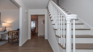 Eine Treppe mit weißen Geländern und Holzboden, die zu einem Essbereich führt.