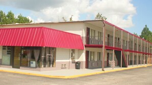Ein zweistöckiges Motel mit rotem Markisenvorbau und überdachtem Außenbereich.