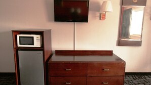 Ein Hotelzimmer mit einem Holzkasten, einer Mikrowelle, einem Fernseher und einem Spiegel.