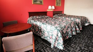 Ein Hotelzimmer mit zwei Betten, einem Holztisch, einem Stuhl und zwei Wandleuchten.
