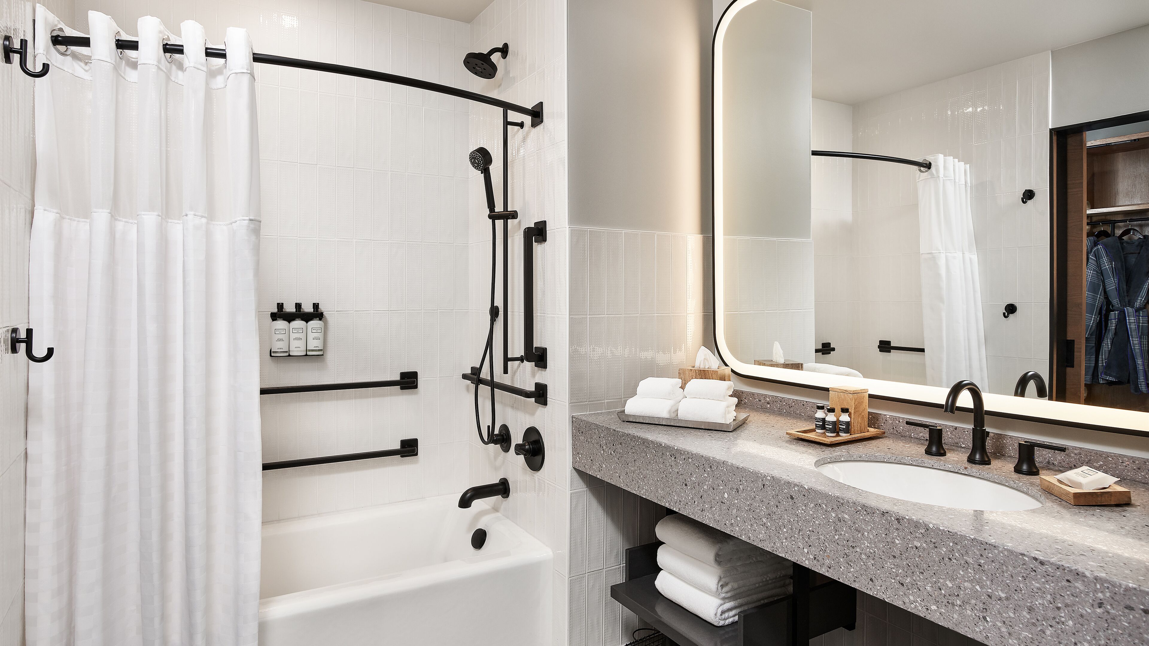 Un baño moderno con bañera, ducha y tocador con un espejo grande.