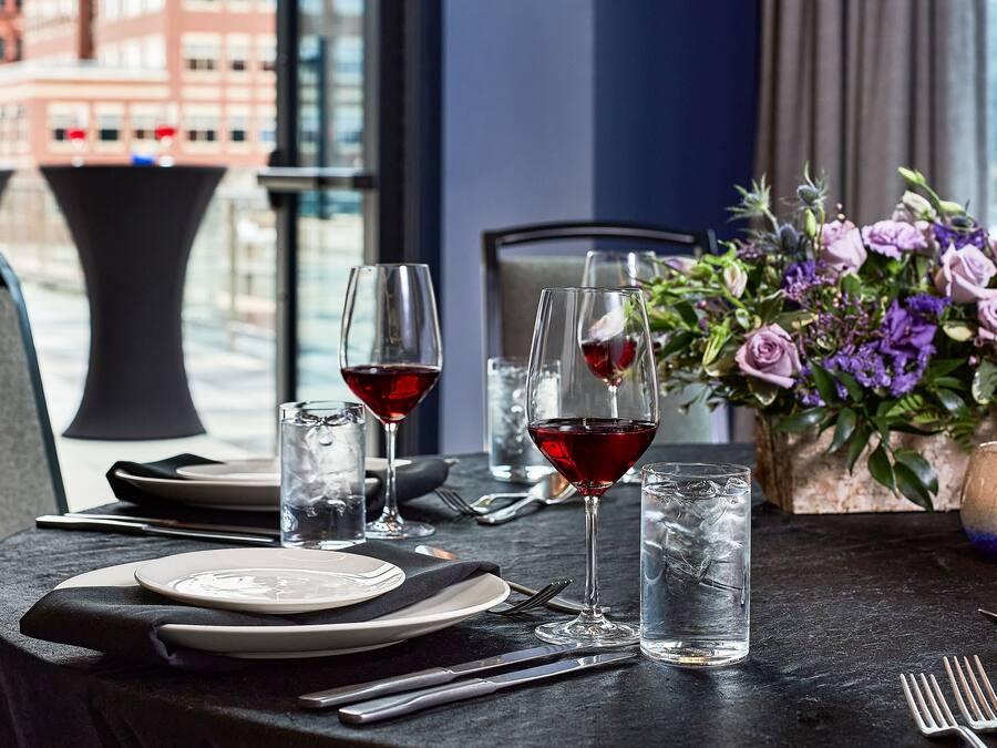 A table set for dining with plates, cutlery, and glasses of red wine.
