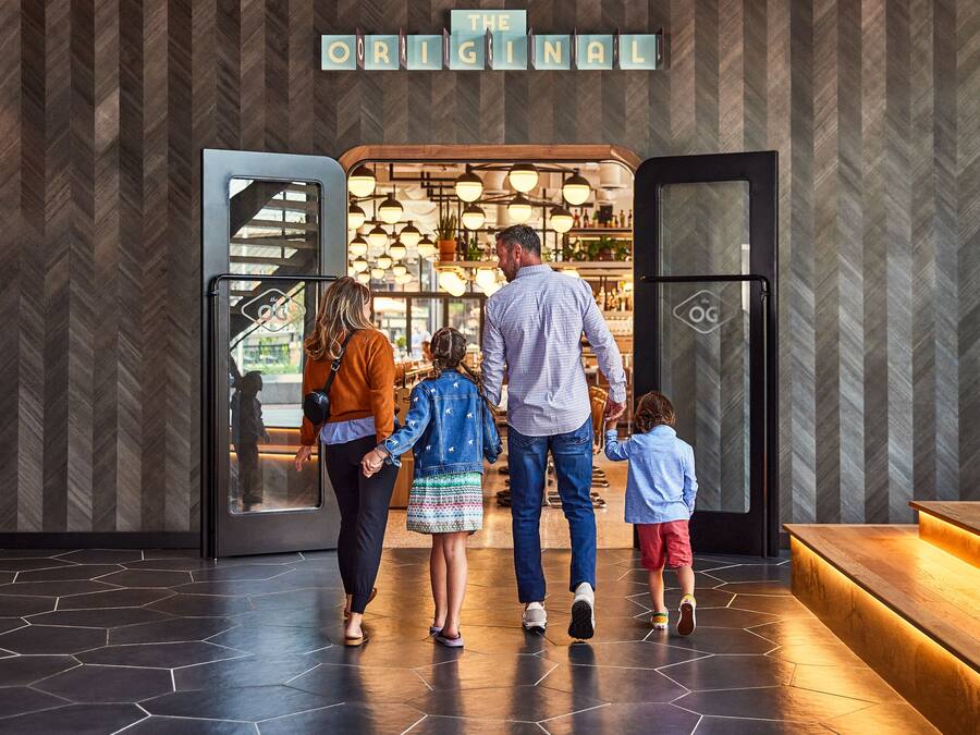 A family walking towards a restaurant with a sign reading "The Original".